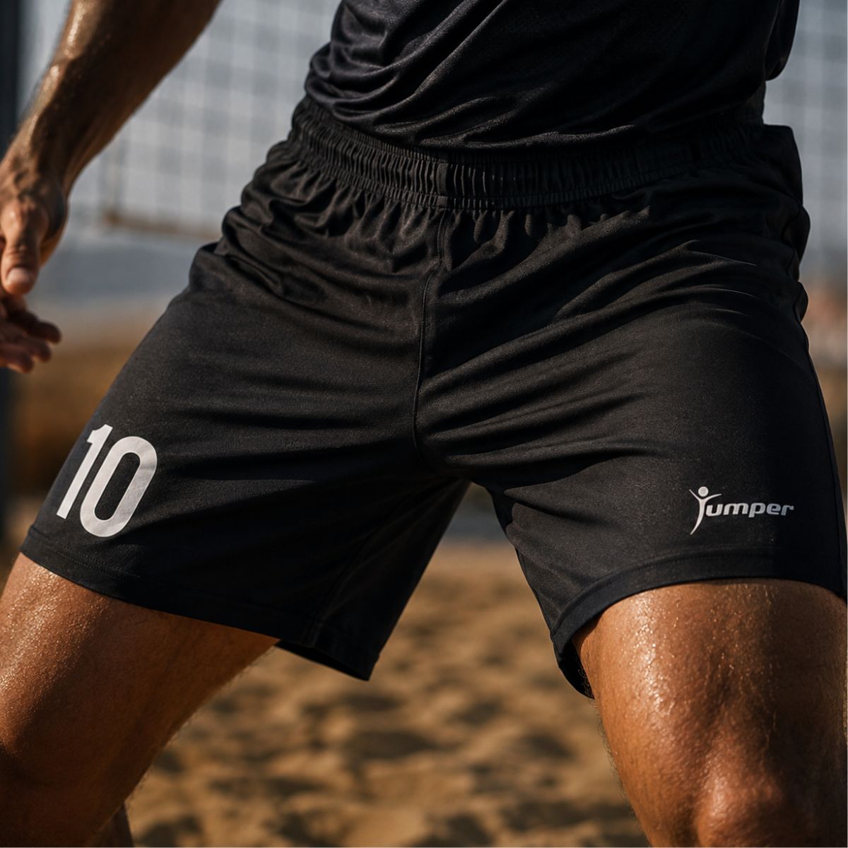 Close-up of an athlete wearing black athletic shorts with the number 10 on the left leg and the Jumper logo on the right leg, outdoors.